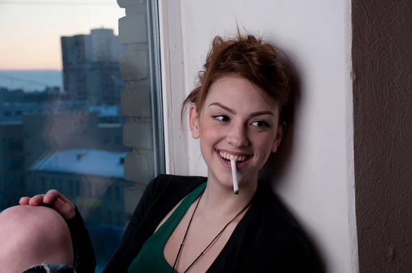 Vacker ung kvinna röka på kvällen fönster. — Stockfoto