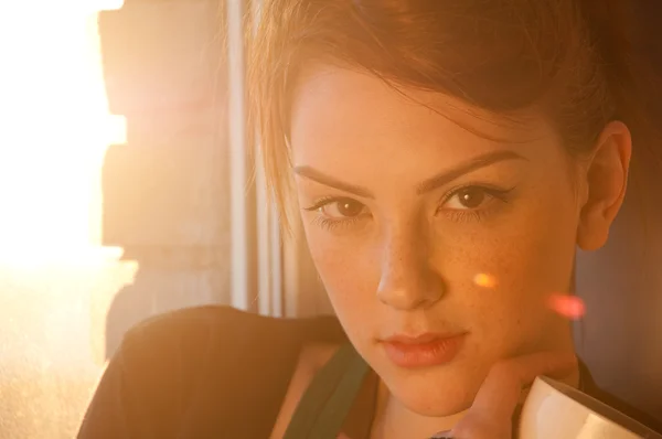 Krásná mladá žena s šálkem horké kávy nad slunce okno — Stock fotografie