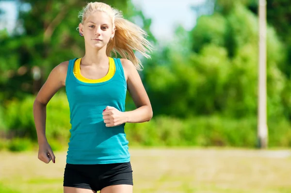 Νεαρή γυναίκα που τρέχει σε καταπράσινο πάρκο — Φωτογραφία Αρχείου