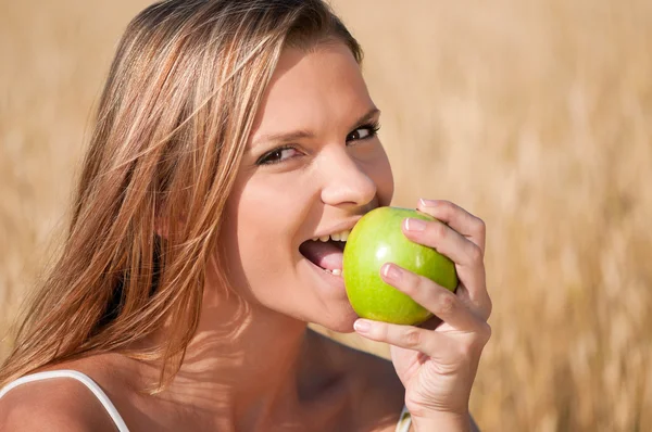 Kadın buğday alan yeme yeşil elma. Yaz pikniği. — Stok fotoğraf