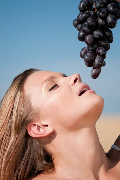 Kobieta w polu pszenicy, jeść winogrona. letni piknik. — Zdjęcie stockowe