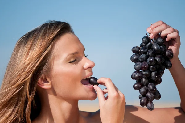 Mujer en el campo de trigo comiendo uvas. Picnic de verano . —  Fotos de Stock