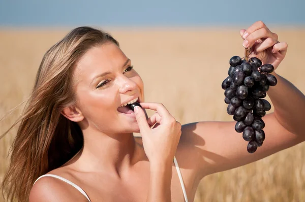 밀 필드 포도 먹는 여자입니다. 여름 피크닉. — 스톡 사진