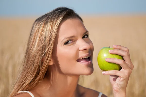 Kvinna i vete fält äta grönt äpple. sommar picknick. — Stockfoto