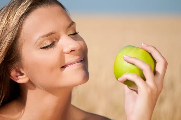 グリーン小麦のフィールドを食べる女性アップル。夏のピクニック. — ストック写真