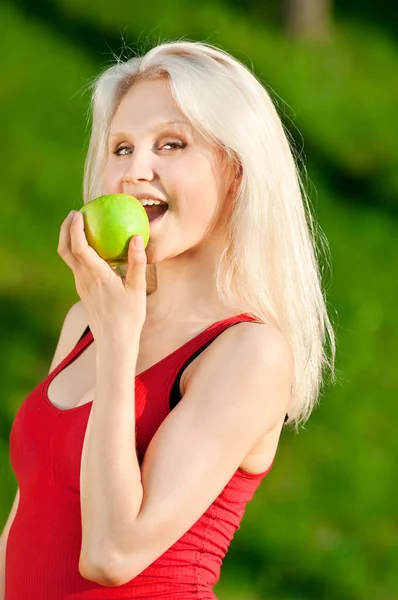 Женщина с зеленым яблоком в парке — стоковое фото