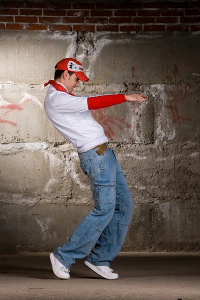 Hip hop boy tančí v moderním stylu nad šedou cihlová zeď — Stock fotografie