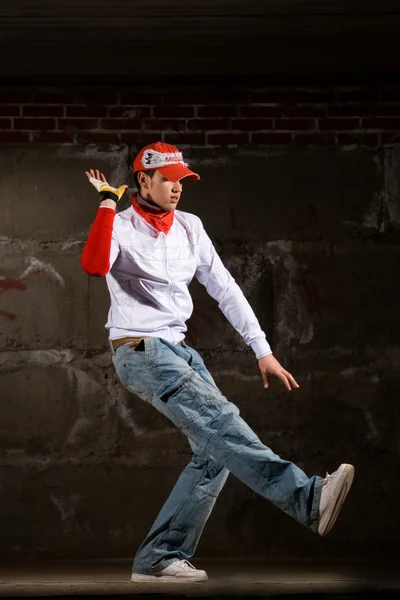 stock image Hip hop boy dancing in modern style over grey brick wall