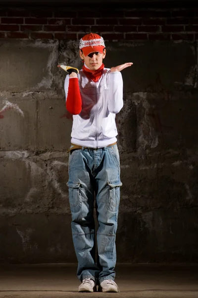 Хип-хоп мальчик танцует в современном стиле над серой кирпичной стеной — стоковое фото