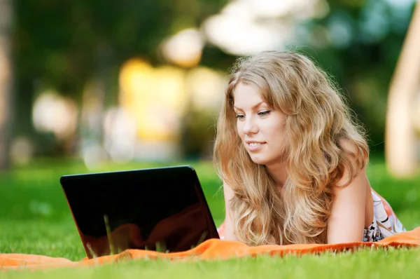 Ung kvinna med laptop på park — Stockfoto