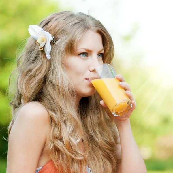 Усміхнена жінка п'є апельсиновий сік — стокове фото