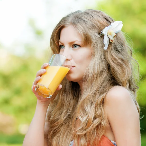 Улыбающаяся женщина пьет апельсиновый сок — стоковое фото