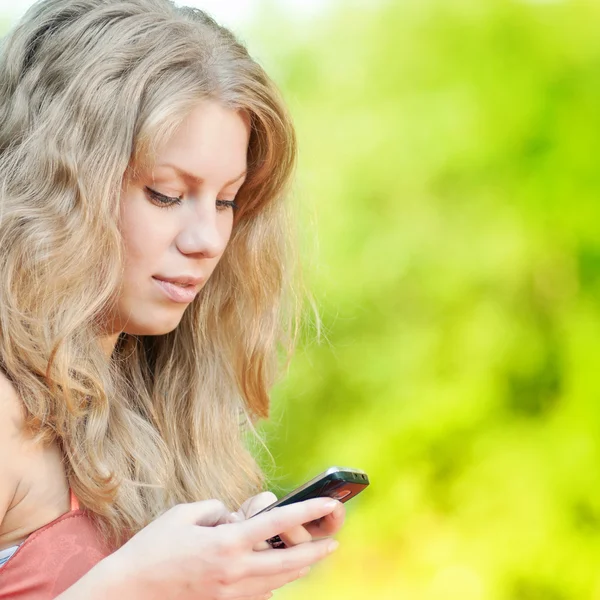 Kobieta smsy na telefon komórkowy — Zdjęcie stockowe