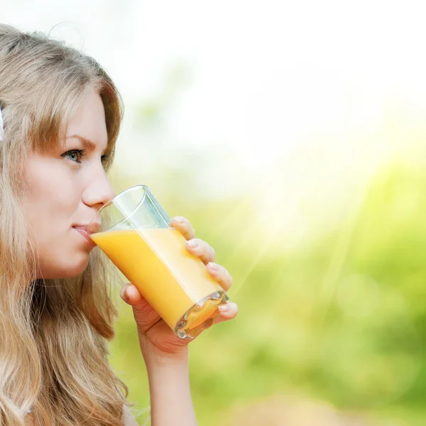 Улыбающаяся женщина пьет апельсиновый сок — стоковое фото
