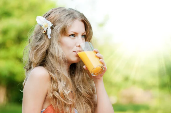 Усміхнена жінка п'є апельсиновий сік — стокове фото