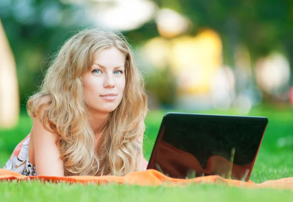Jonge vrouw met laptop op park — Stockfoto