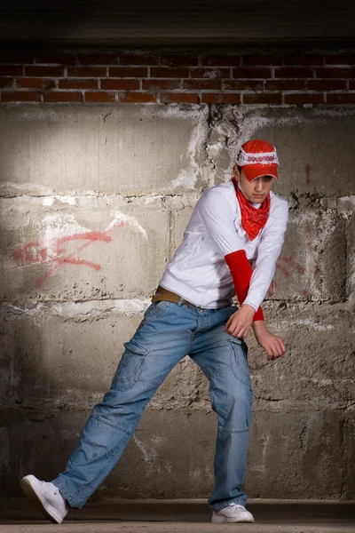 灰色のレンガの壁の上にモダンなスタイルで踊るヒップホップの少年 ストックフォト