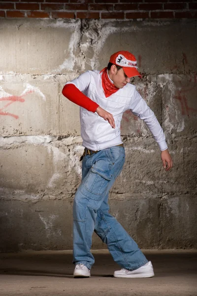 灰色のレンガの壁の上にモダンなスタイルで踊るヒップホップの少年 ストック写真