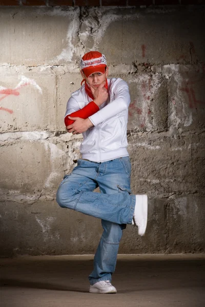 在灰色砖墙跳舞在现代风格的嘻哈男孩 免版税图库图片