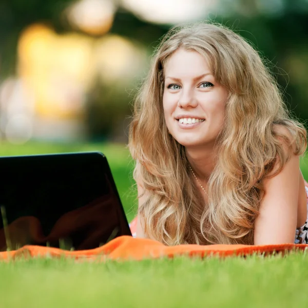 Jonge vrouw met laptop op park Stockfoto