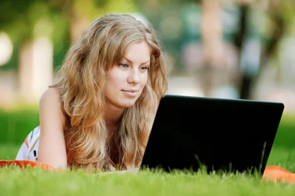 Junge Frau mit Laptop im Park Stockbild