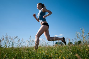 Sport woman running over green grass and sky clipart