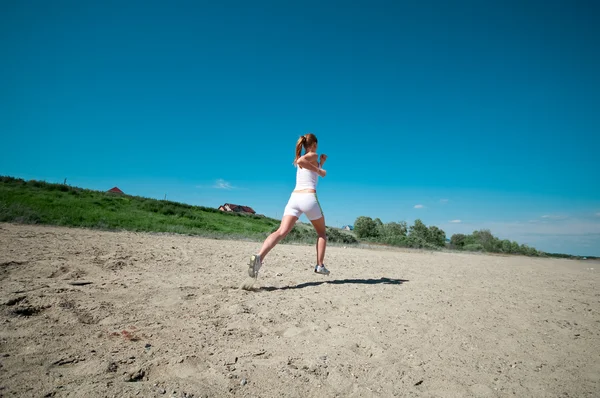 Спортивна жінка біжить на морському узбережжі — стокове фото