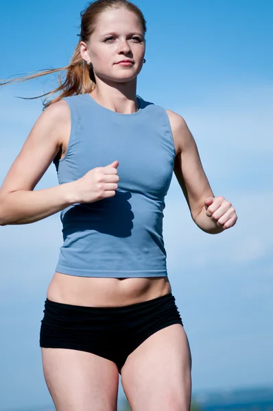 Спортивная девочка-подросток бежит по голубому небу — стоковое фото