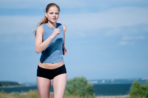 Jovem mulher do esporte correndo no dia ensolarado — Fotografia de Stock