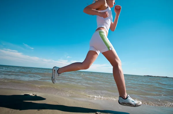 Спортивная женщина бегает по морскому побережью — стоковое фото