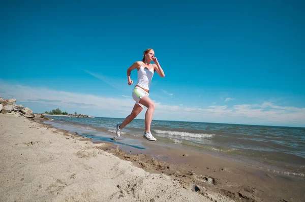 Спортивная женщина бегает по морскому побережью — стоковое фото