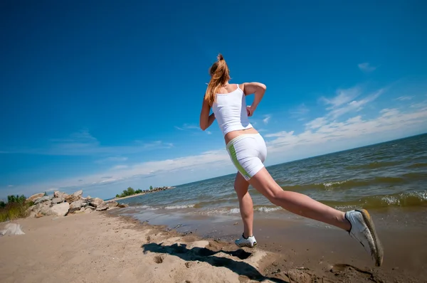 Sport kvinde kører på stranden - Stock-foto