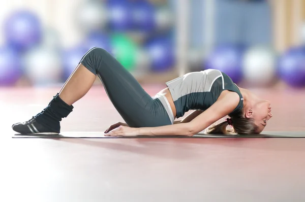Kvinna gör stretching fitness motion på sport gym. Yoga — Stockfoto