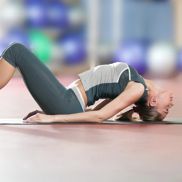 Женщина делает упражнения на растяжку в спортзале. Йога — стоковое фото