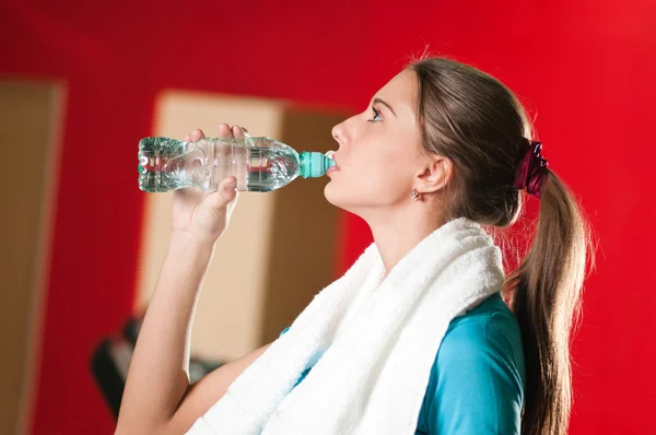 Женщина в спортзале пьет воду — стоковое фото