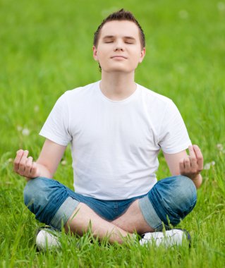 Park yoga yaparken genç bir adam