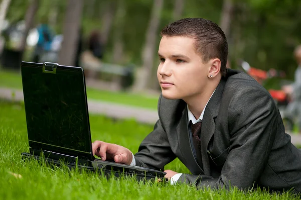 Biznes człowiek działa na notebooka w parku. uczeń — Zdjęcie stockowe