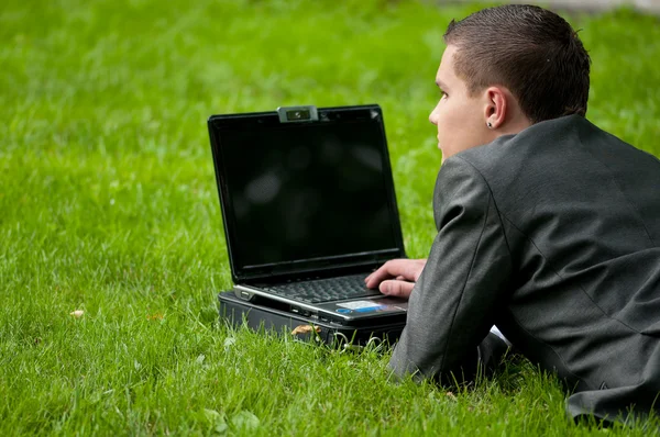 Biznes człowiek działa na notebooka w parku. uczeń — Zdjęcie stockowe