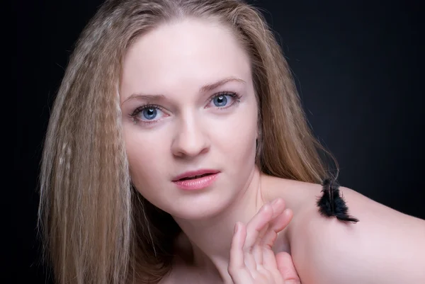 Nahaufnahme Porträt eines blonden Mädchens mit Feder auf Schwarz — Stockfoto