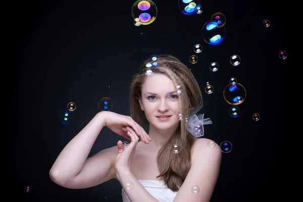Närbild porträtt av blond flicka med såpbubblor på svart — Stockfoto