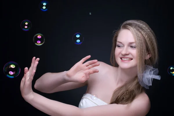 Closeup portrait of blond girl with soap bubbles on black — Stock Photo, Image