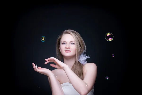 Closeup portrait of blond girl with soap bubbles on black — Stock Photo, Image