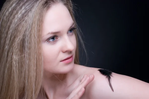 Close up portrait of blond girl with feather on black — Stock Photo, Image