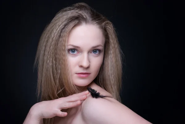 Nahaufnahme Porträt eines blonden Mädchens mit Feder auf Schwarz — Stockfoto