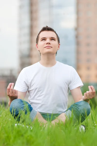 Ein junger Mann macht Yoga im Park Stockbild