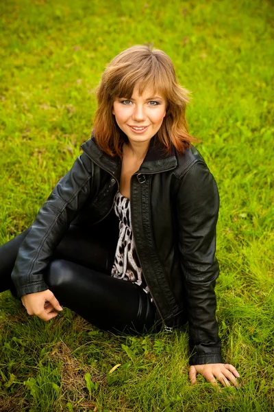 En ung brun-håret pige på græs baggrund - Stock-foto
