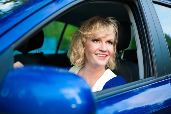 Blonde girl at the wheel of blue car — Stock Photo, Image