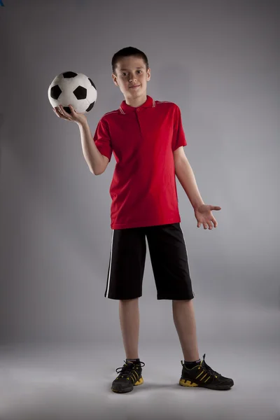 Мальчик с футбольным мячом позирует в студии — стоковое фото