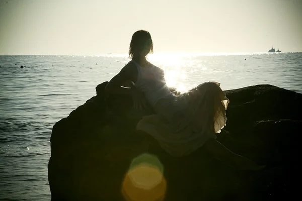Silhouette di giovane donna in mare sullo sfondo del tramonto — Foto Stock