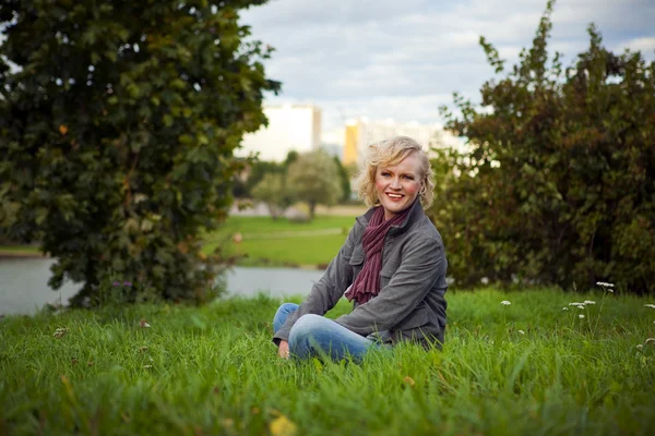 Nehir kıyısında oturan kadın gülüyor — Stok fotoğraf
